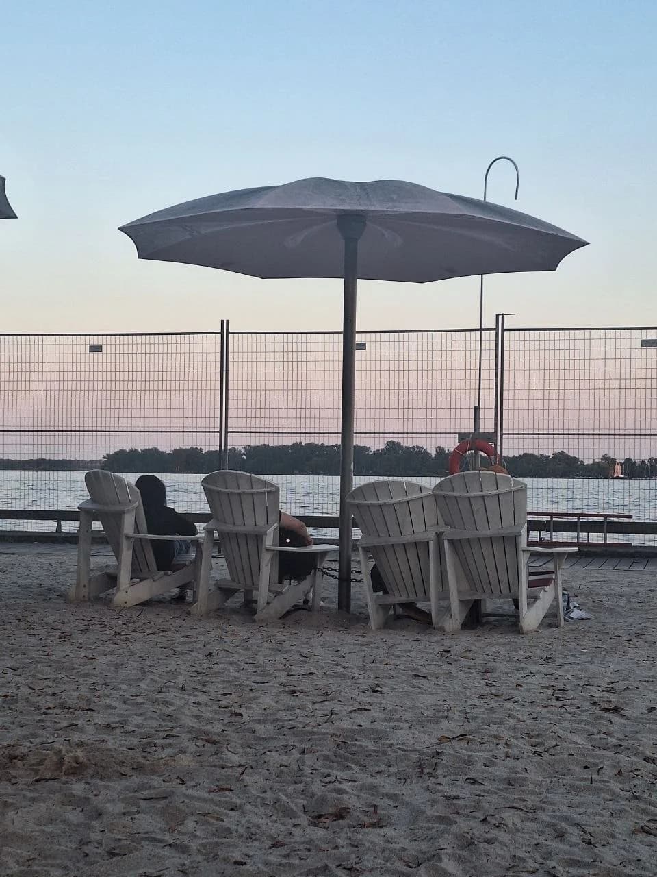 A beach umbrella and empty chairs at dusk